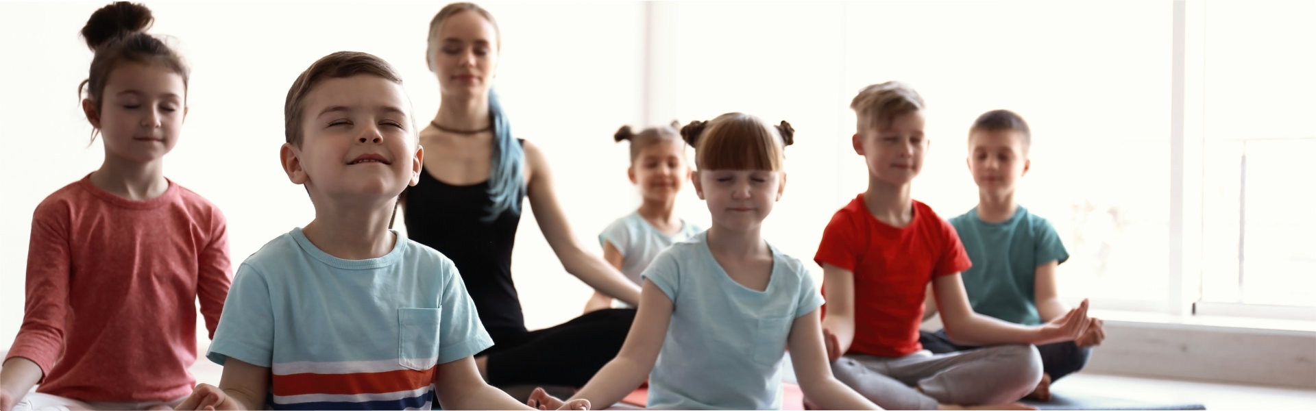 Little children and their teacher practicing yoga in gym