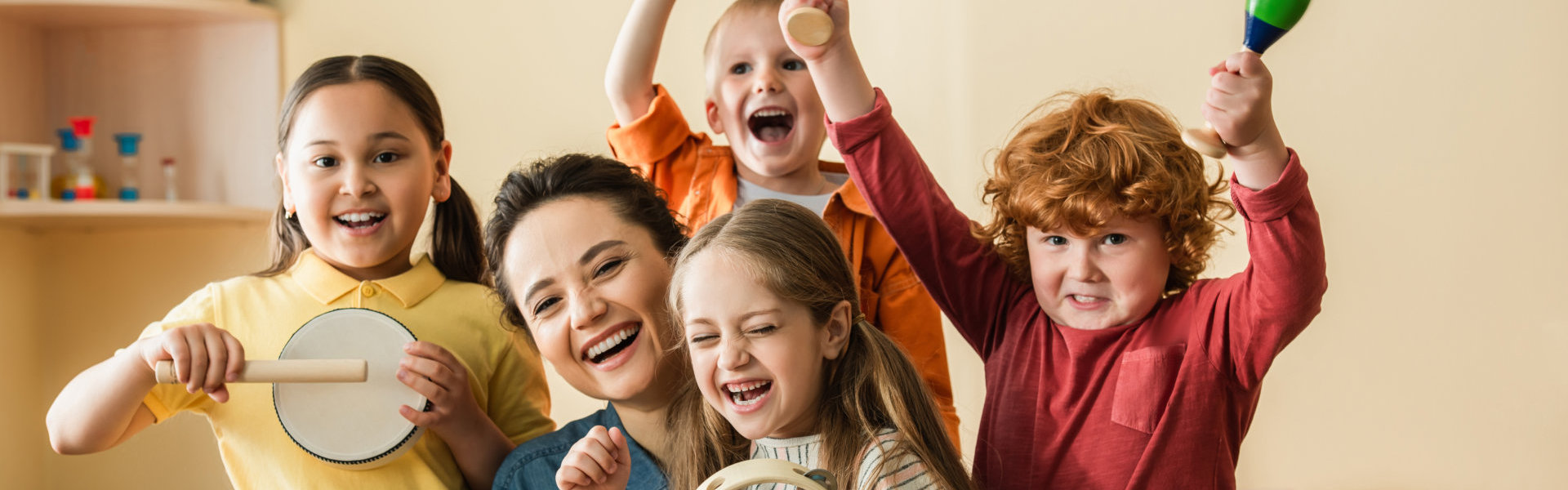 excited  kids playing musical instruments near happy teacher