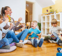 Kindergarten teacher with children sitting on the floor having music class, using various instruments and percussion.