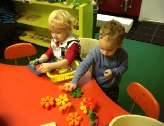 Two kids happily playing with toys in a colorful play room.