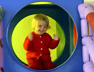 Kid having fun in play area with circular mirror.
